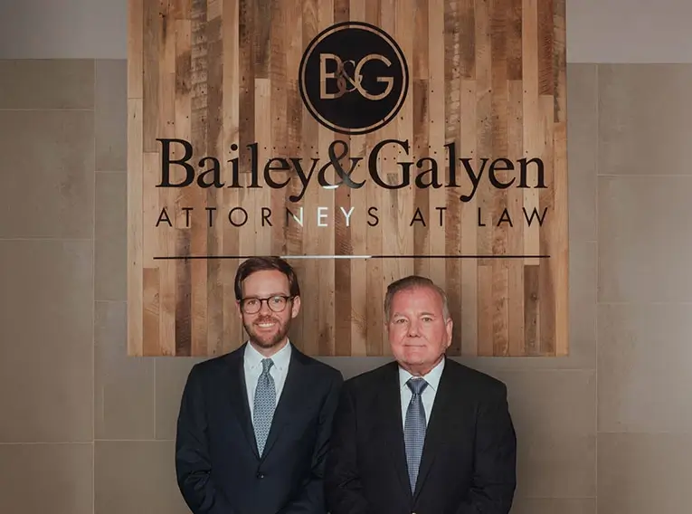 Bailey & Galyen attorneys standing beneath the firm's logo at the office